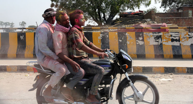 Three on a bike during Holi